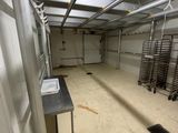 une grande pièce avec de nombreux rayonnages métalliques et des tables