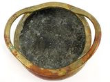 a small metal bowl with a handle on a white surface