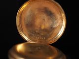 a close up of a gold pocket watch on a black surface