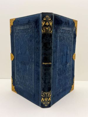 un vieux livre bleu aux bords dorés posé sur une table blanche