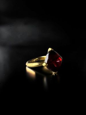 a gold ring with a red stone on a black surface