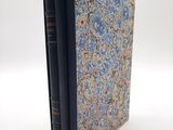 un vieux livre à la couverture bleue posé sur une table blanche