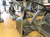 row of stationary exercise bikes in a gym with a television in the background
