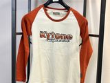 un t-shirt à manches longues orange et blanc suspendu à un portant