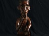 une statue en bois représentant un homme, la main posée sur le menton