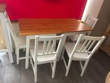 a table and four chairs in a room with a clock on the wall