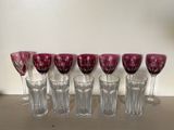 six wine glasses are lined up on a shelf next to a lamp