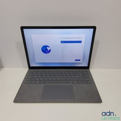 L'ordinateur portable est posé sur la table, l'écran allumé.