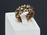 a close up of a gold ring with green and white stones