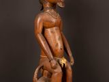 une statue en bois représentant un homme avec un chien sur les genoux