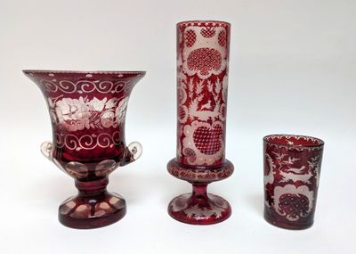 three vases and a glass on a white surface