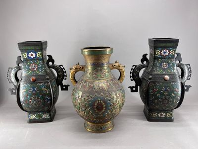 Trois vases sont posés sur une table devant un fond blanc.
