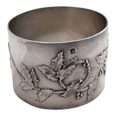 a close up of a silver cuff with holly leaves and berries on it