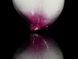 a white vase with a pink flower on it on a black surface