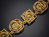 un bracelet en or orné de quatre motifs en spirale sur fond noir