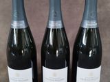 Trois bouteilles de vin mousseux sont alignées sur une table