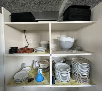 many plates and bowls on the shelves in the kitchen