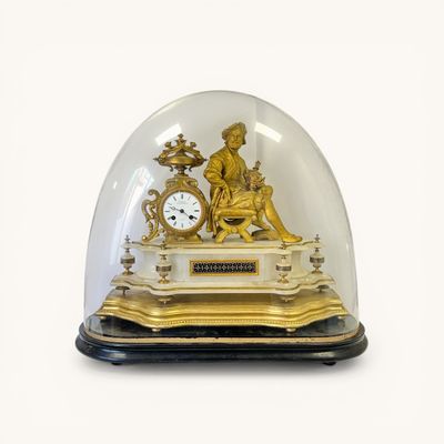 a gold clock under a glass dome on a table