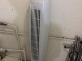 a white fan sitting on the floor next to a radiator