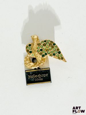 une broche dorée et verte sur laquelle est représenté un oiseau
