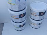 several buckets of paint sitting on a white surface next to a wall