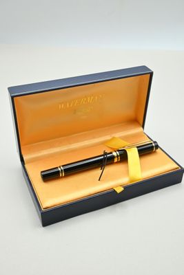 un stylo noir dans une boîte ornée d'un ruban jaune