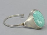 a close up of a silver ring with a green stone on it