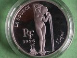 a close up of a silver coin with a nude woman on it
