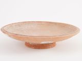 a small bowl on a stand on a white surface