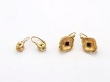 a pair of gold earrings and a pair of earrings on a white surface