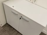 a white cabinet in the corner of a room with a mirror