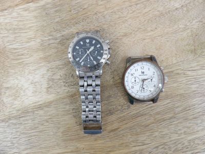 two watches sitting on a wooden table next to each other