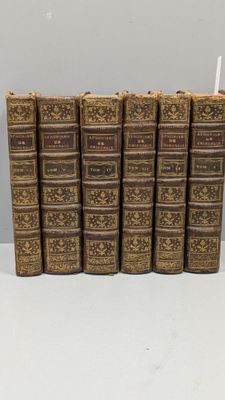 six vieux livres sont alignés sur une surface blanche