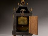 an antique clock with a man on top of it with a door open