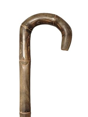 une vieille canne en bois avec un pommeau en métal, sur fond blanc