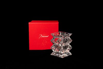 une image représentant un petit vase en cristal posé devant une boîte rouge