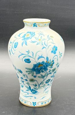 a white vase with blue flowers on it on a table