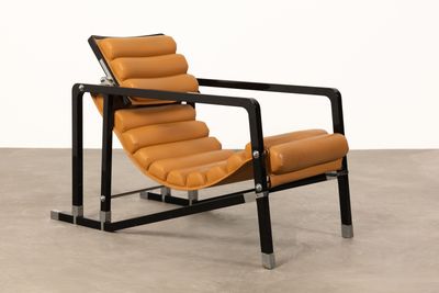 un fauteuil en cuir orange posé sur un sol en béton