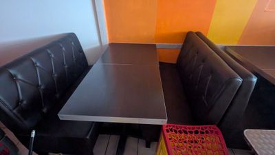 tables and benches in a restaurant with a colorful wall behind them
