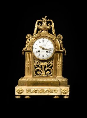 a gold clock that is sitting on a black surface