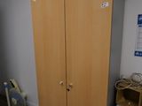 une armoire en bois placée dans un coin de la pièce, à côté d'un bureau