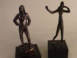 two bronze statues of a man and a woman on black bases