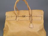 a tan leather handbag on a grey background