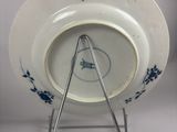 a white plate with blue flowers on it on a stand