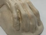 a white sculpture of a hand holding something on a white surface