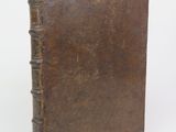 an old brown book sitting on top of a white surface
