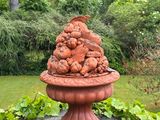 a statue of a bird sitting on top of a bowl of fruit