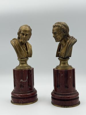 une paire de bustes en bronze représentant un homme et une femme, posés sur des socles