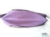 purple leather handbag on white surface with black trim
