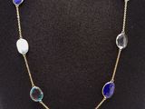 a gold necklace with blue and white glass beads on a mannequin